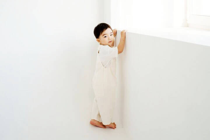 Foto de um menino oriental nas pontas dos pés, como se quisesse crescer, para poder ver através da janela. O menino usa camiseta branca, macacão branco e está em um quarto branco. A foto ilustra o artigo Por que desconstruir os seus padrões comportamentais por meio da sua aceitação e da sua transformação escrito pelo psicanalista Homero Mônaco para o site Online Psicanalista.Foto de uma menina com perna levantada como se fosse pisar na lente da câmera que a fotografa. A foto ilustra o artigo Alcançar a Paz e o Encerramento de Decepções Passadas escrito pelo psicanalista Homero Mônaco para o site Online Psicanalista.