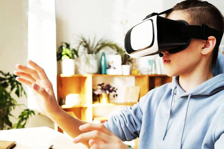 Foto de um menino utilizando óculos de realidade virtual. A foto ilustra o artigo Os Impactos Causados pela Inteligência Artificial: Social, Comportamental, Psicológico e Cognitivo escrito pelo psicanalista Homero Mônaco para o site Online Psicanalista.
