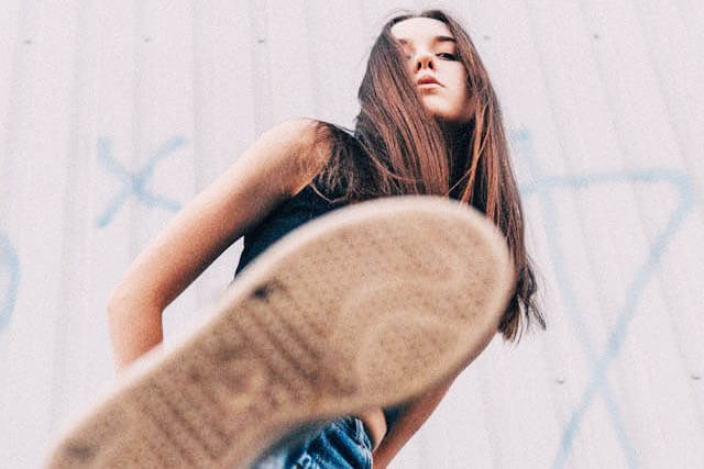 Foto de uma menina com perna levantada como se fosse pisar na lente da câmera que a fotografa. A foto ilustra o artigo Por que desconstruir os seus padrões comportamentais por meio da sua aceitação e da sua transformação escrito pelo psicanalista Homero Mônaco para o site Online Psicanalista.